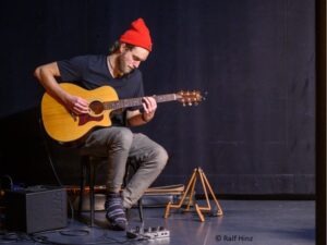 Ein Mann mit roter Mütze spielt Gitarre.