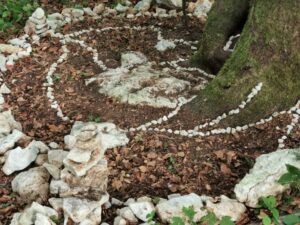 Steine, Hölzer und Blätter sind um einen Baumstamm gelegt